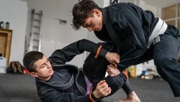 Two jiu jitsu BJJ athletes training at the academy martial arts ground fighting sparring wear kimono gi sport uniform on the tatami mats sports jiujitsu and self-defense concept